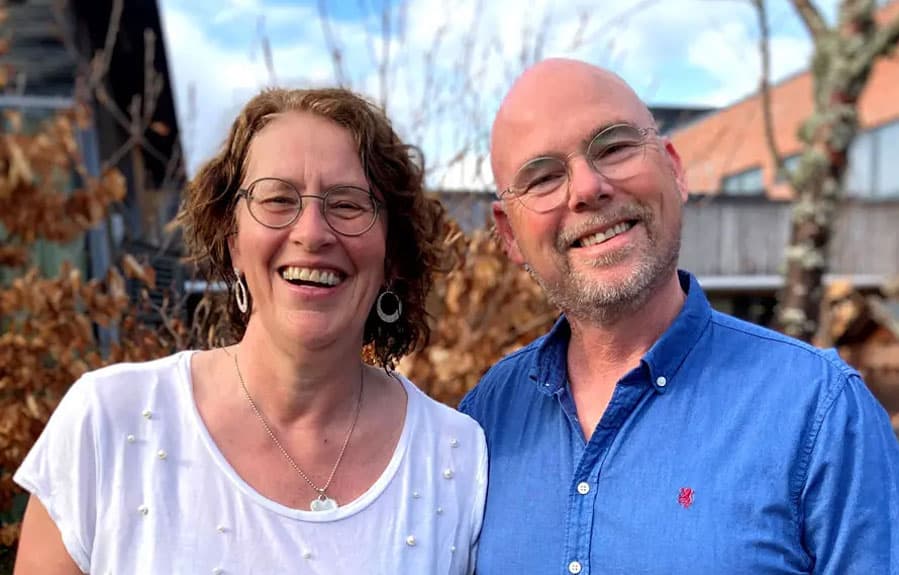 Et ektepar står side om side og smiler.