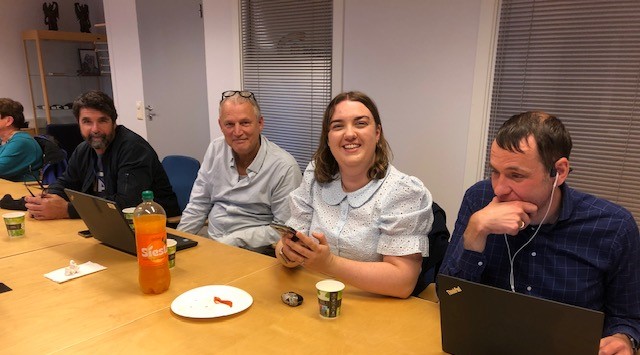 Personer følger ivrig med på at en synshemmet person tester en applikasjon med mobilen sin.