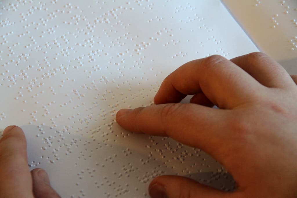 Fingre som leser på et punktskriftark