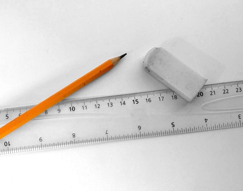 Bilde av en gul blyant som ligger på et lyst ark, sammen med en linjal og et viskelær.