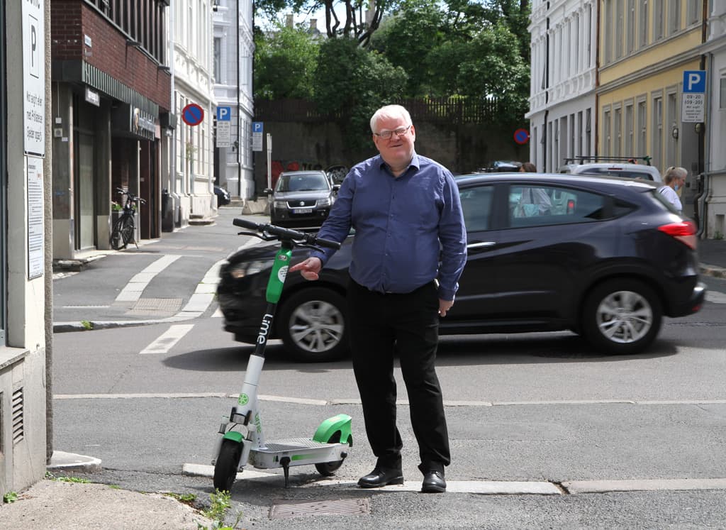 Leder i Norges Blindeforbund Terje Andrè Olsen står på fortauet ved siden av en elsparkesykkel.