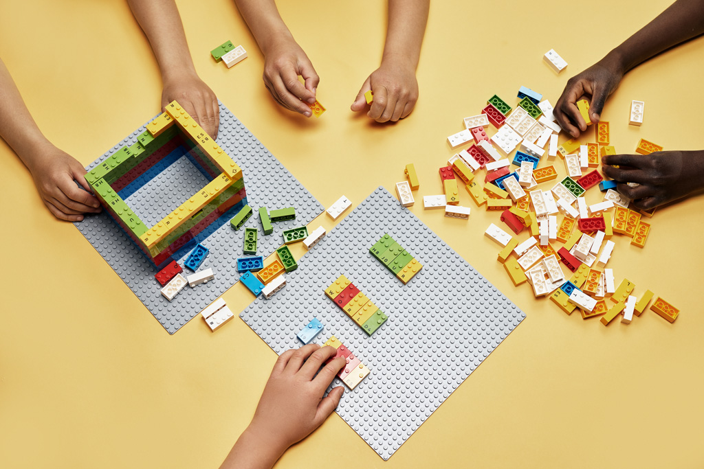 barnehender som bygger LEGO-braille på gulvet.