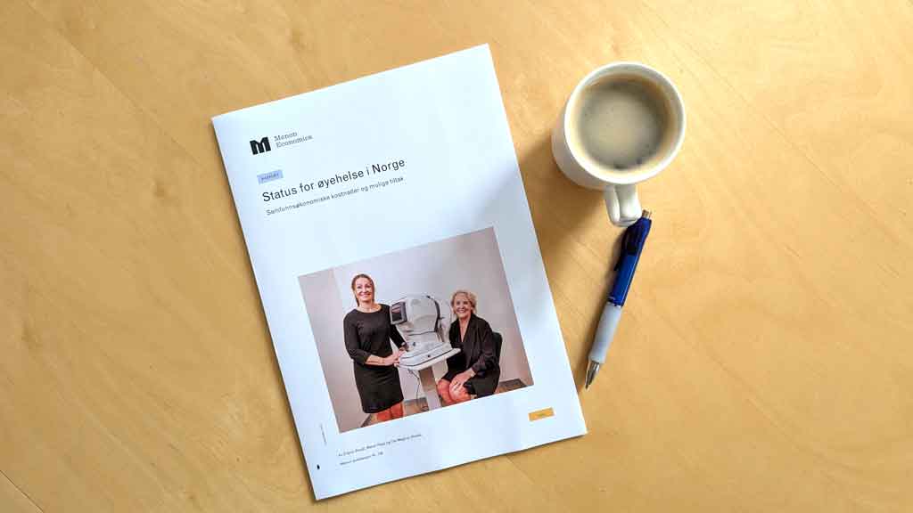 Bilde av rapporten liggende på et bord, sammen med et krus m,ed kaffe og en kulepenn.