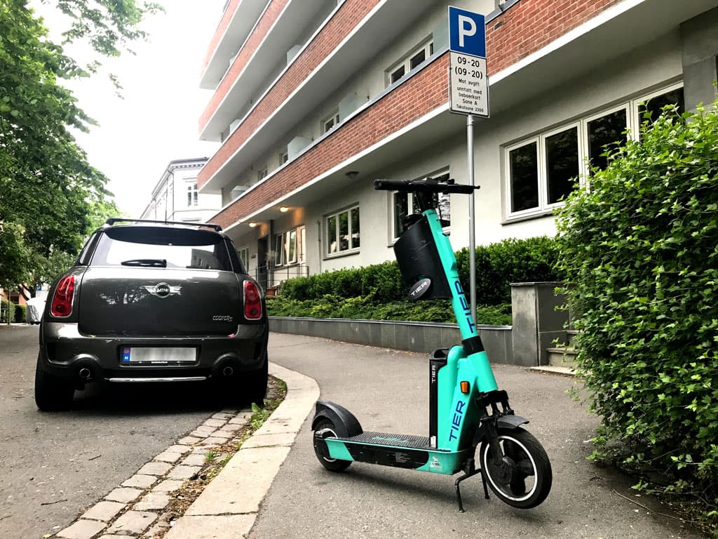 En elsparkesykkel står parkert på tvers på et smalt fortau.