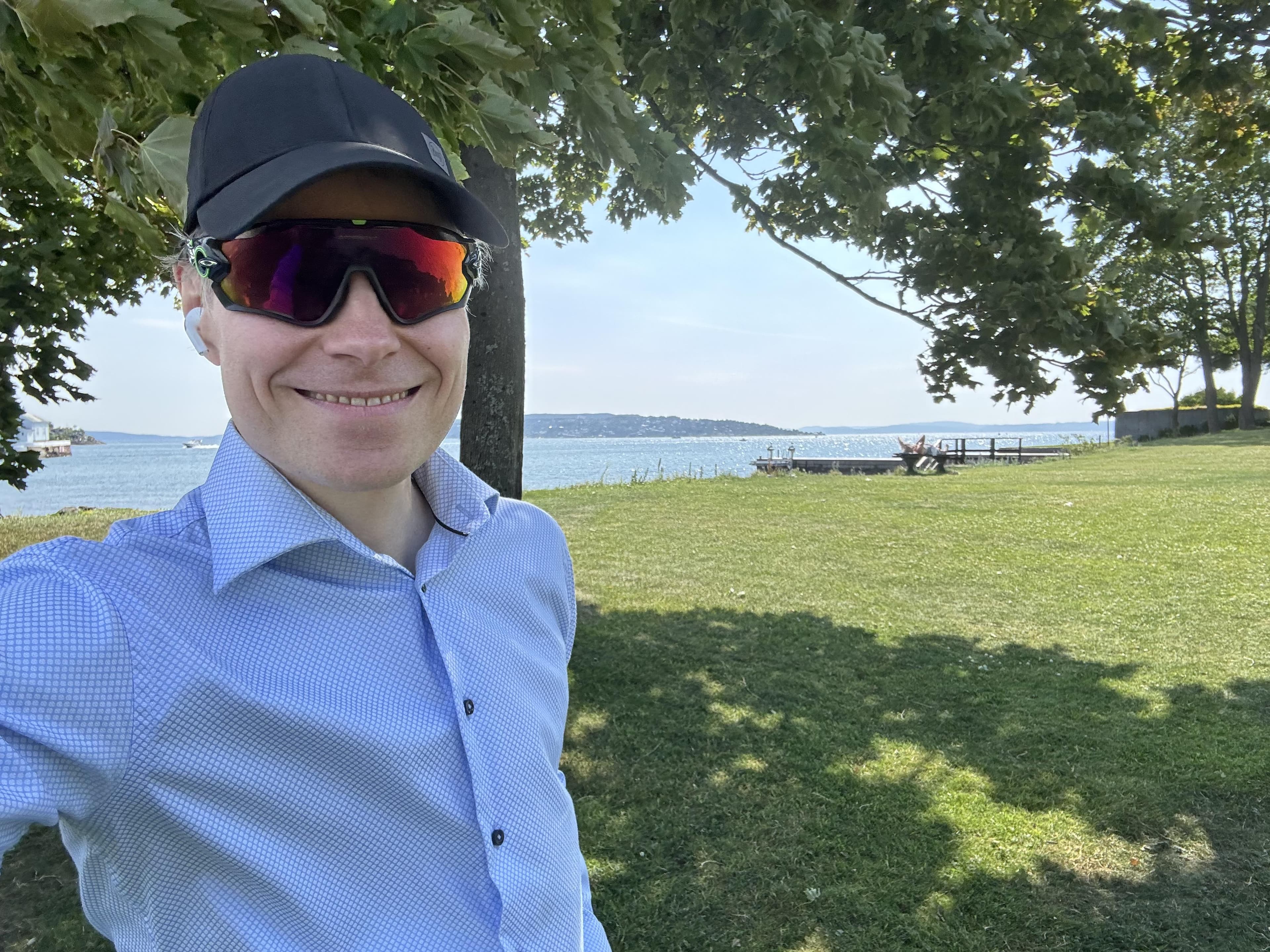 En smilende mann med solbriller og caps.