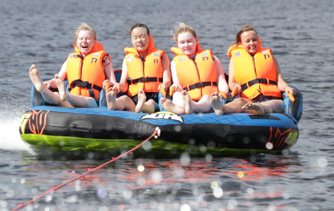 Fire jenter i full fart i tuben bak båten på Hurdalsjøen