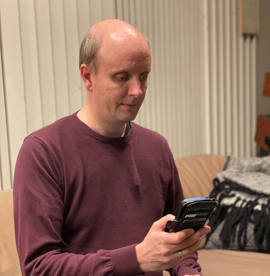 Yngve sitter med en mobiltelefon i hånden.