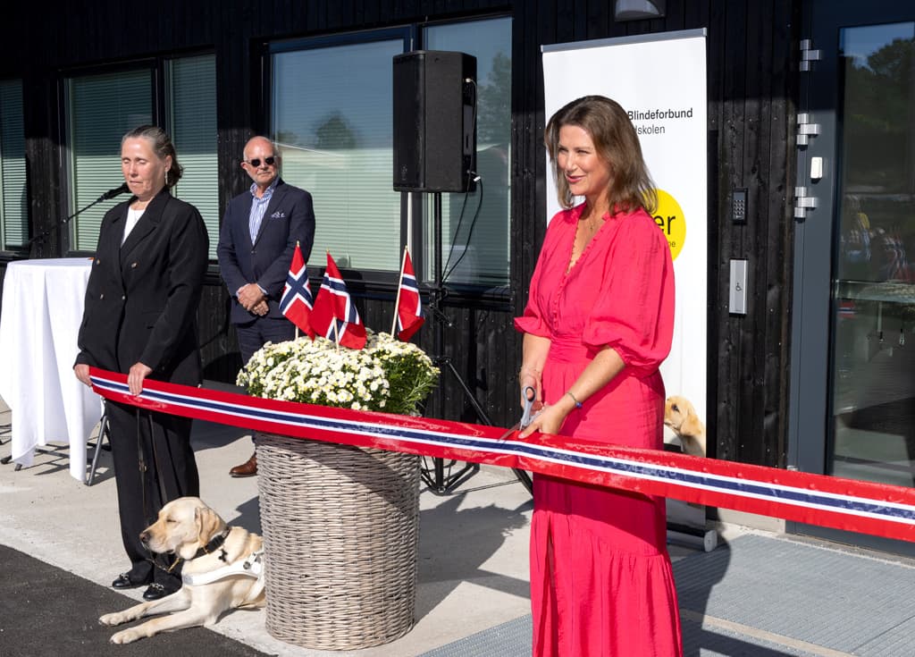 til venstre Anne Tveten med sin lyse labrador førerhund, holder båndet som Prinsessen klippet over. Prinsessen til høyre