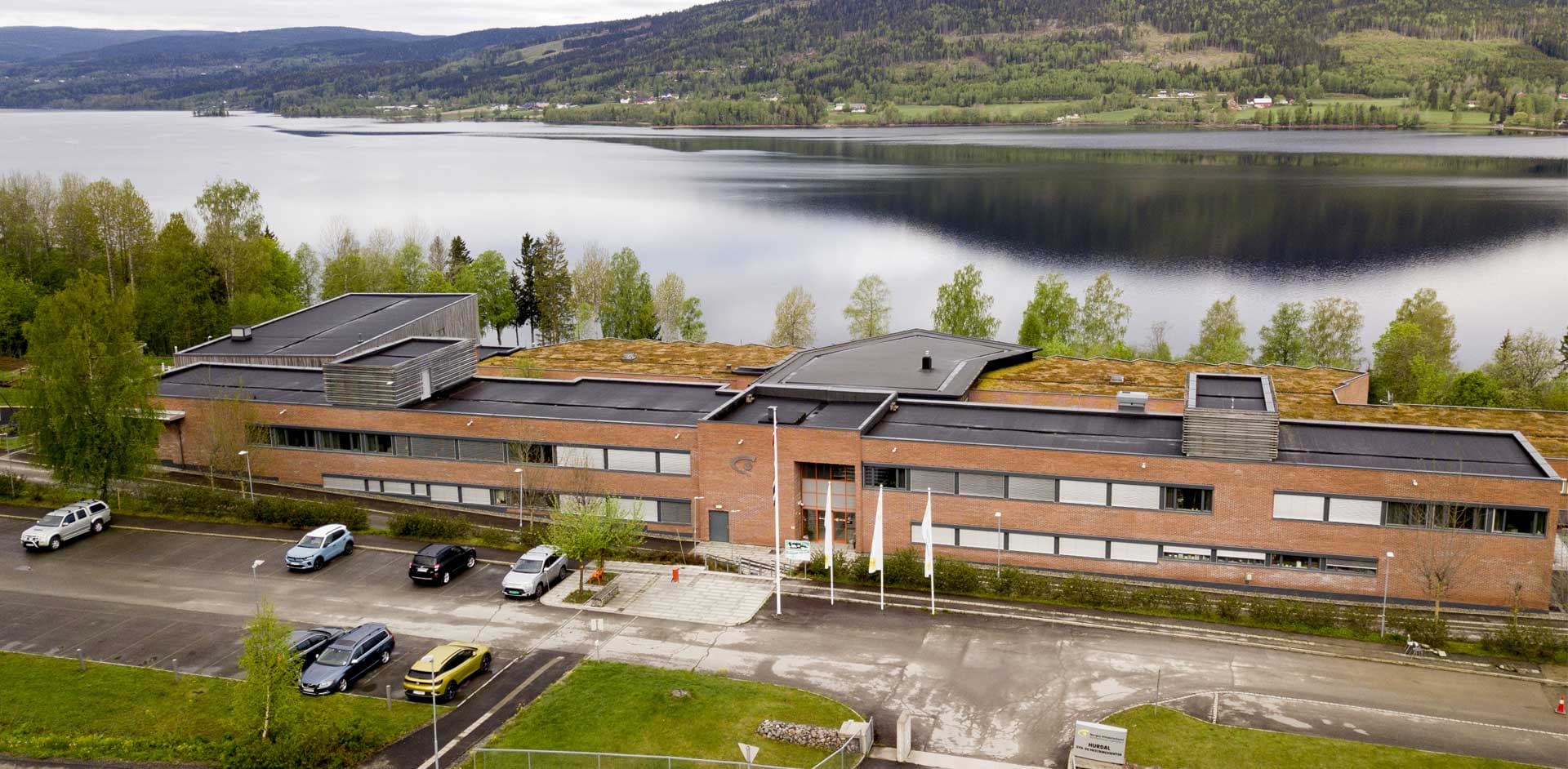 Hurdam syn og mestringssenter sett fra luften. Inngangsparti i midten nede, Hurdalsjøen i bakgrunnen